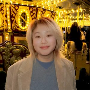 Lea Liu, MEng student at the Department of Aeronautics, standing in front of a lit carousel.