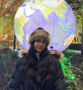 Natasha Patnaik wearing a winter coat and hat, standing in front of a large inflatable model of the earth.