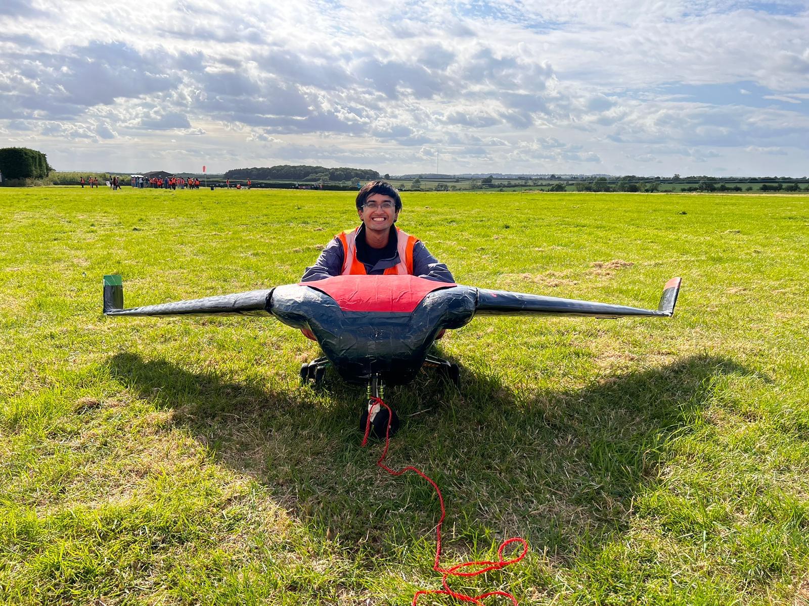 Yash poses in a field with a glider.