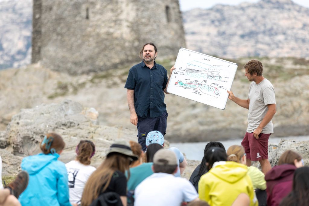 Valentin Laurent and Mark Sutton hold a whiteboard during a fieldwork session.