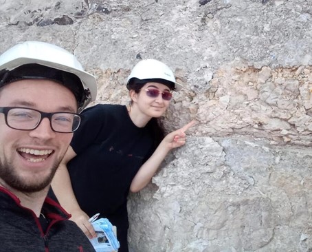 Isabelle and Mark in Denmark, pointing at the rock marking the extinction of the dinosaurs.