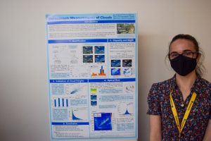 A photo of Katie standing next to her Masters project poster, titled "Stereoscopic Measurements of Clouds"