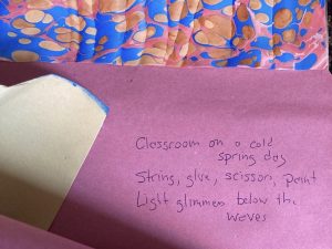 Stephen's poem hidden in his craftwork, reads: Classroom on a cold spring day. String, glue, scissors, papers. Light glimmers below the waves.