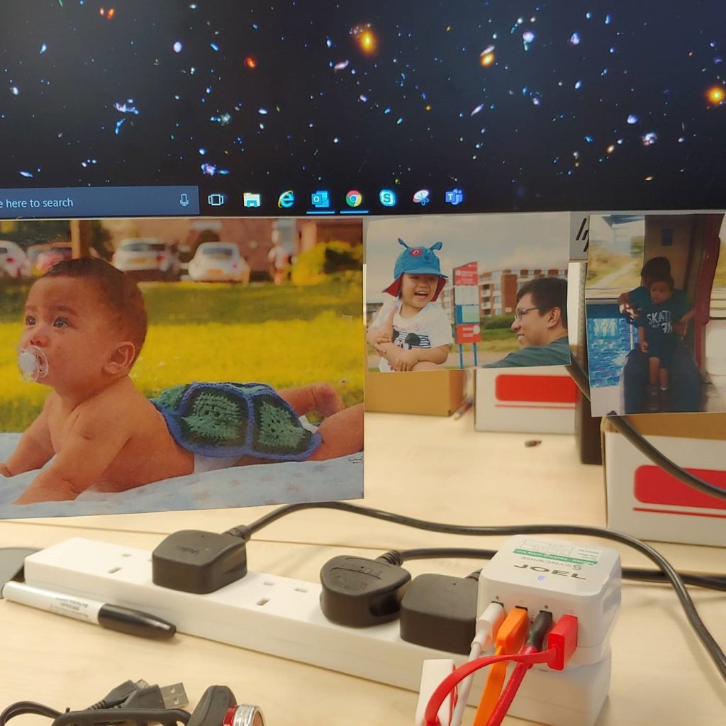 Image shows several photos of Joel and his son stuck to the bottom of his PC screen