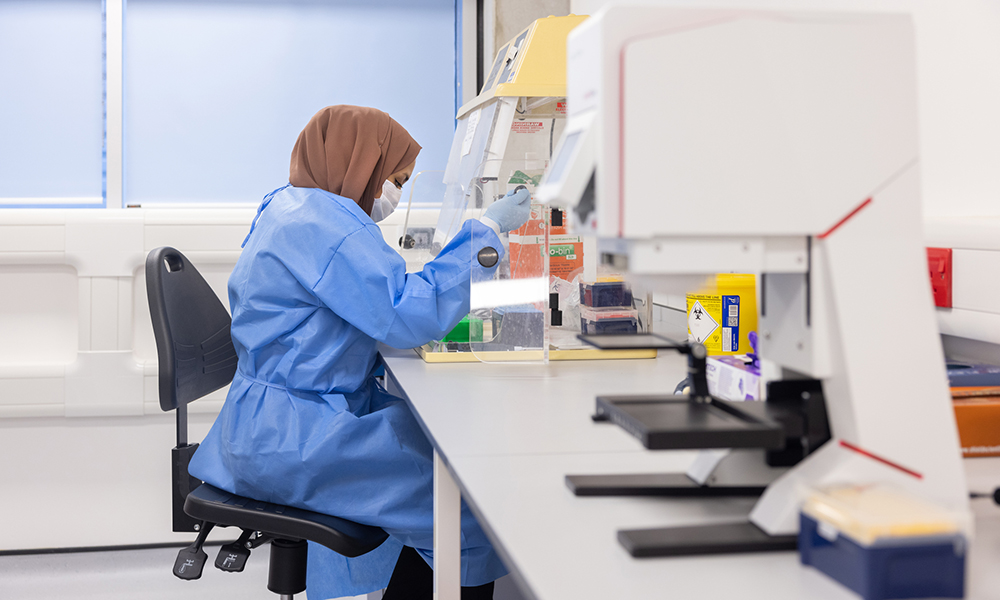 A researcher working at a lab bench in a blue lab coat