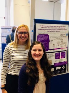 A photograph of Lindsay presenting a poster of her research with one of the young people she worked with.