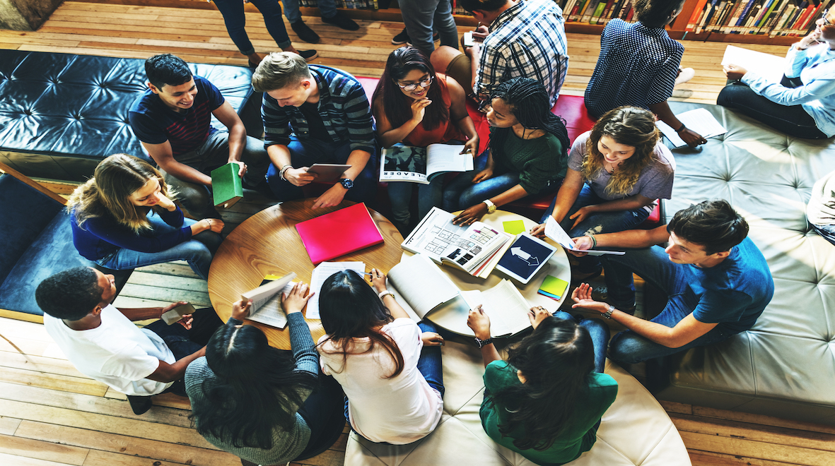 A group of students sitting around a table talking and reading 