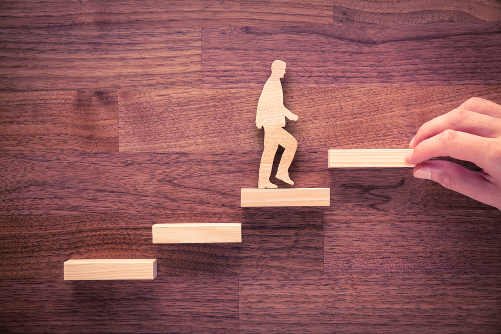 A figure of a man made from wood walking up stairs