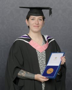 Ingrid Logan in a graduation gown holding a medal