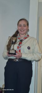 Jess Money in her Scout leader uniform, holding her award for District Beaver Scout Leader of the Year