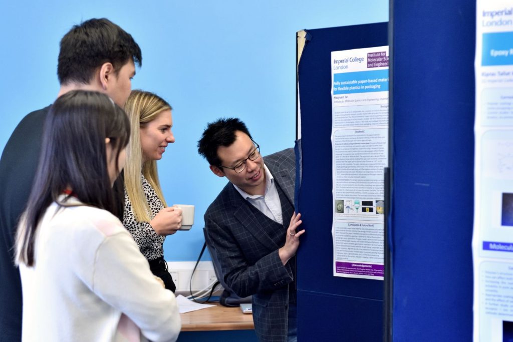 A group of students and science professionals discuss a student's poster