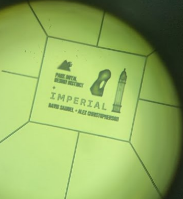 Photo taken through the lenses of a microscope. From left to right, miniature PRDD and Imperial logo, sculpture and Queens Tower. The nanoscribe 3D printer was used to print these objects onto a glass slide.