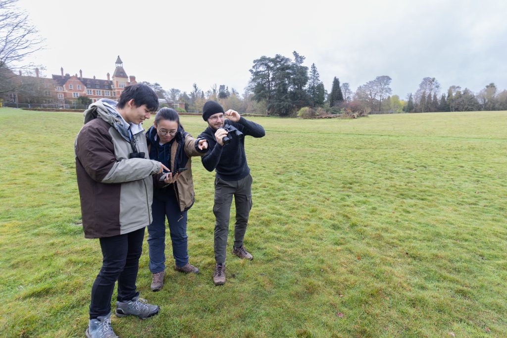 The team on a transect survey. They are looking over a grassy green field.