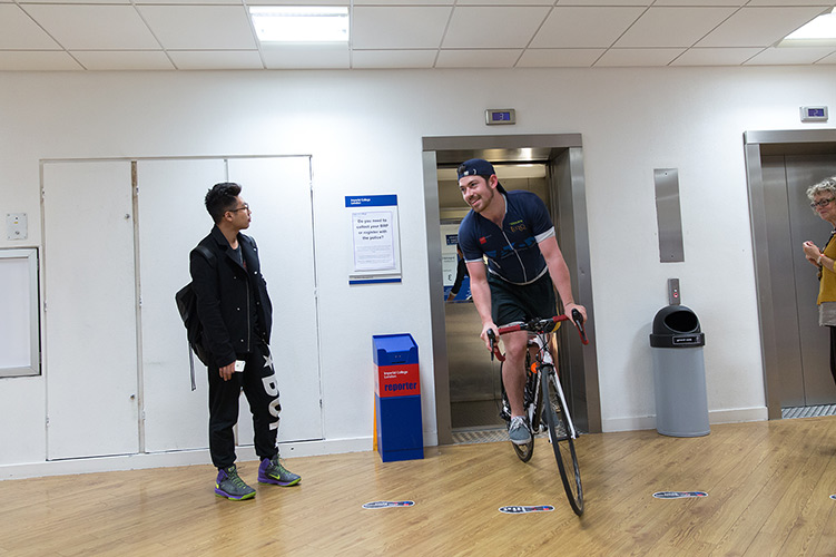 A student on a bike cycles out of a lift.