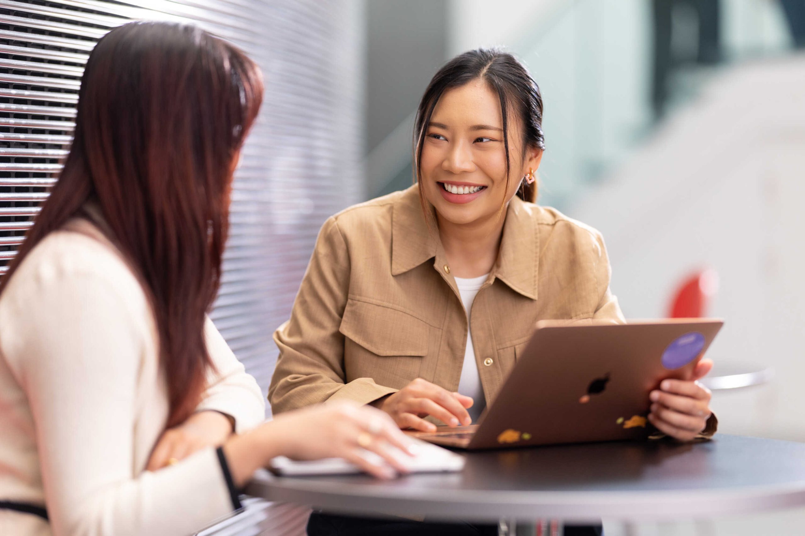 Two Imperial students sitting on a round table, working on a laptop together