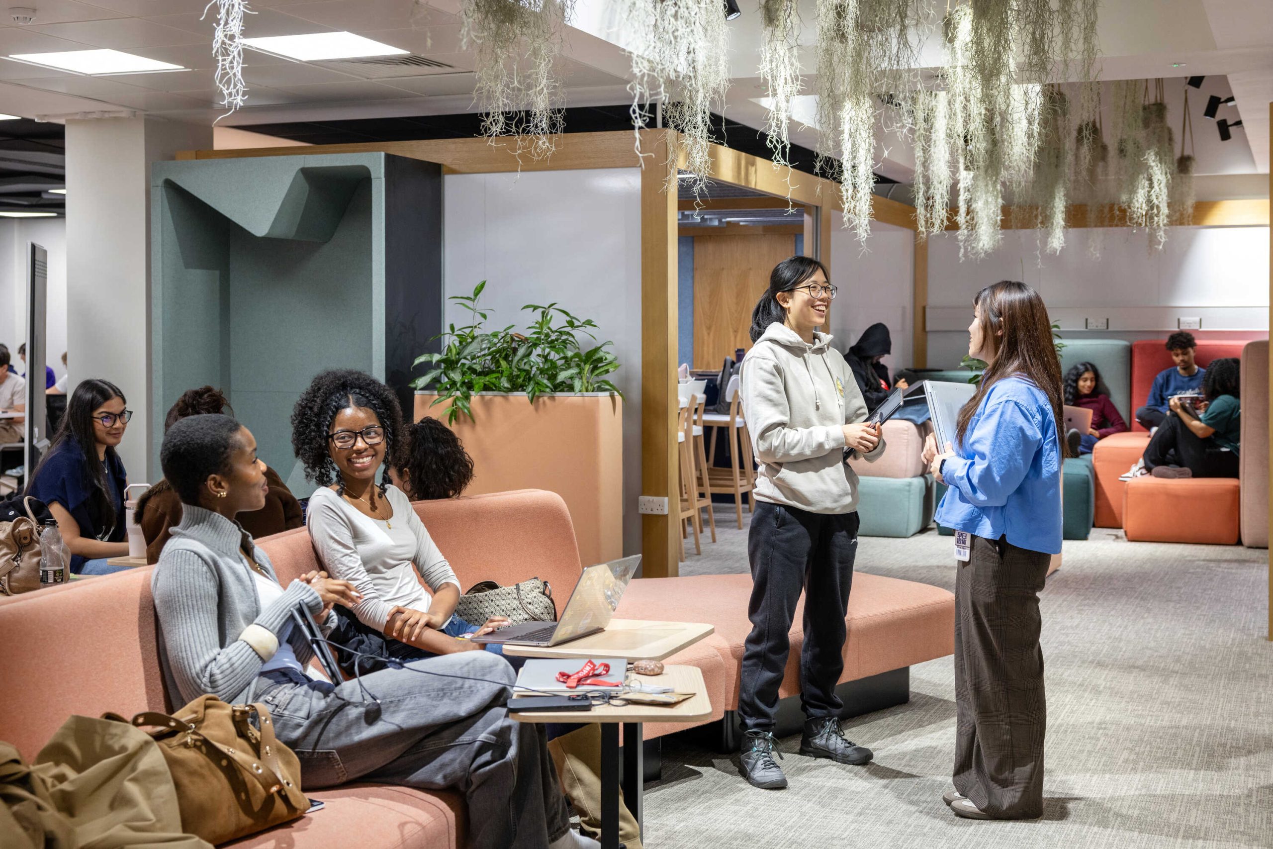 Imperial College London students relaxing in a shared student space with various couches, chairs and indoor plants