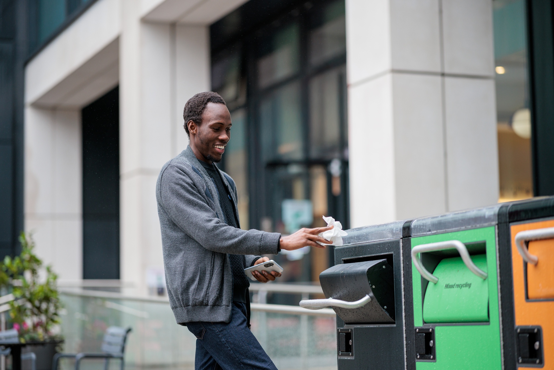 A student puts waste paper in a general waste bin on Imperial's South Kensington Campus